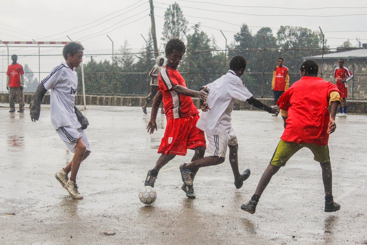 Youth playing a competitive soccer game in the rain, showcasing teamwork and energy.